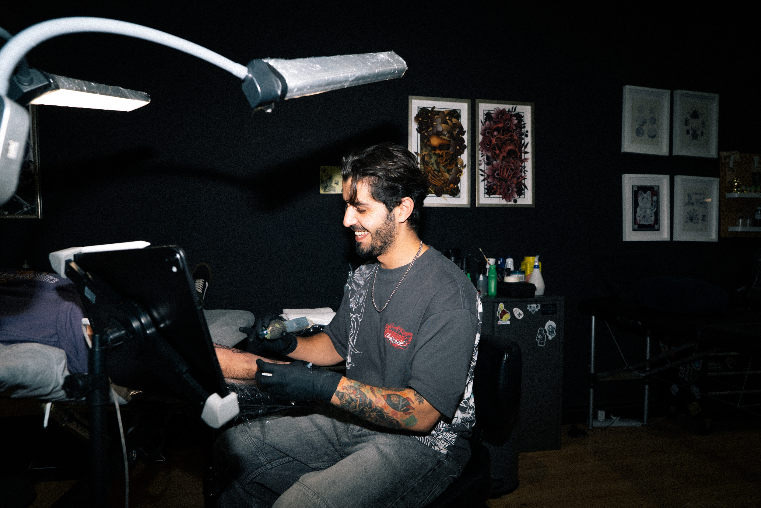 A Full Moon artist smiling while tattooing under the ring light
